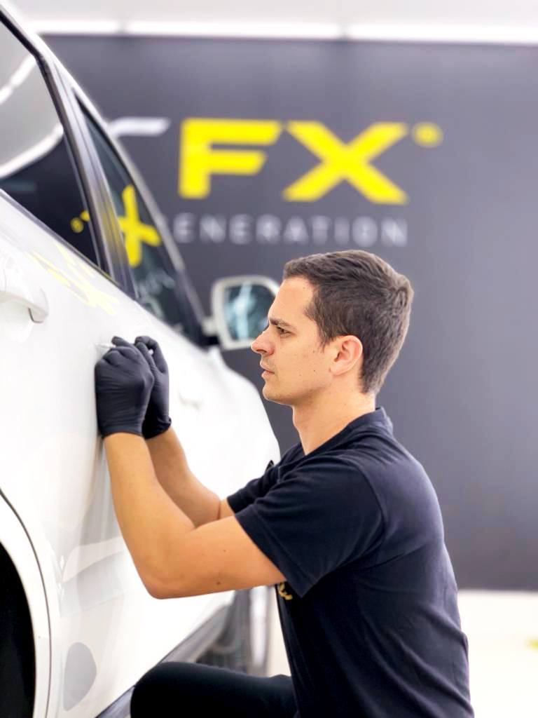 Technician applying RestorFX product onto vehicle's surface during paint restoration process