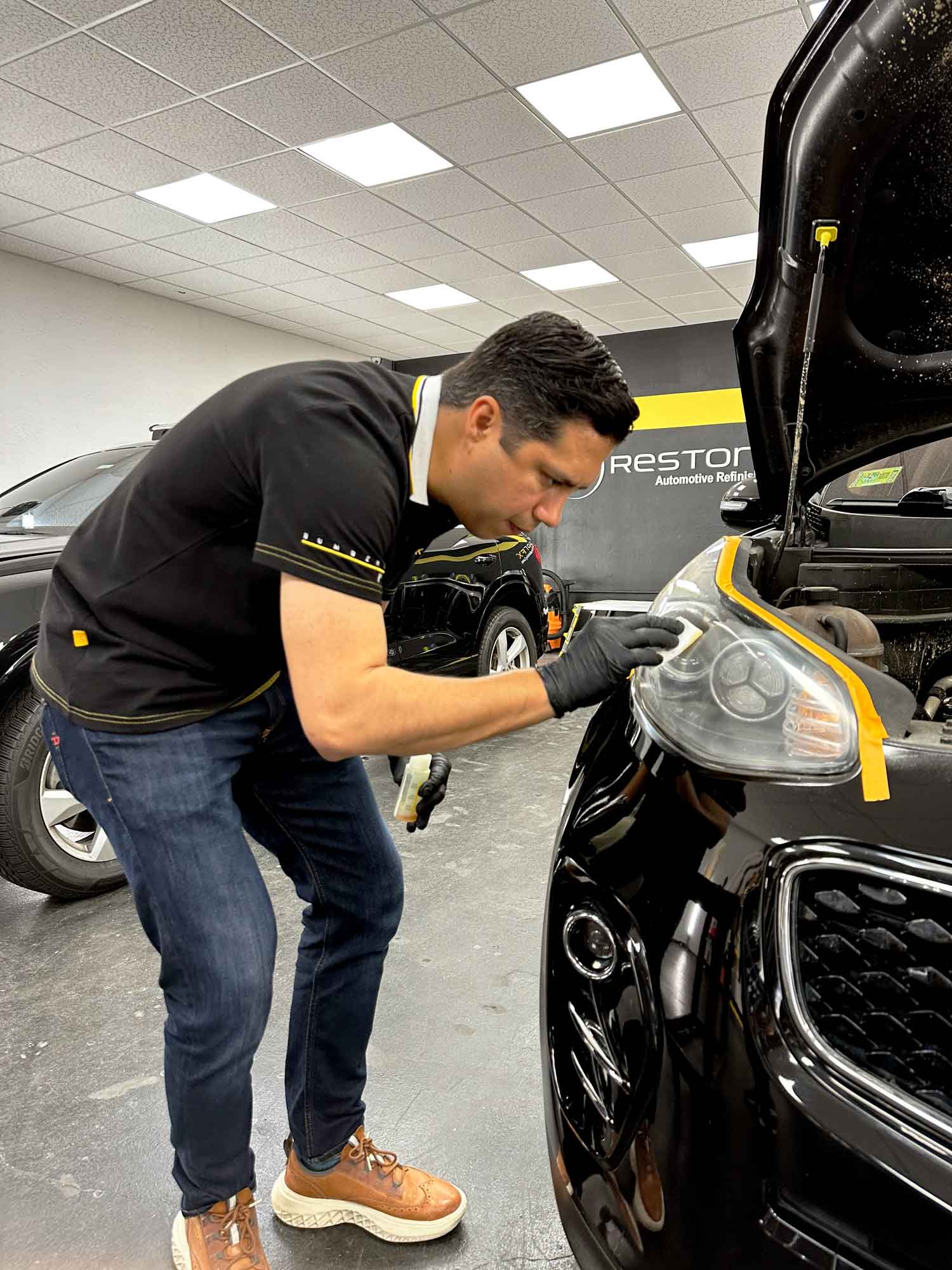 Técnico de RestorFX Tegucigalpa aplicando producto a camioneta negra con guantes puestos